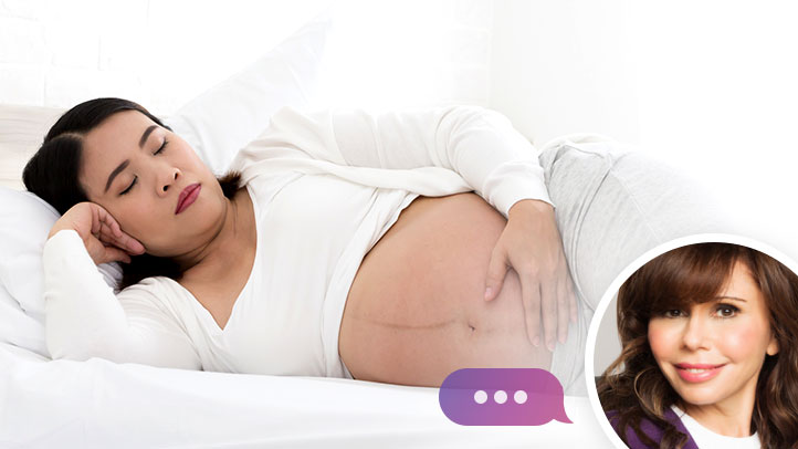 Ask Heidi Murkoff, why does baby kick more at night, pregnant woman in bed with hand on stomach