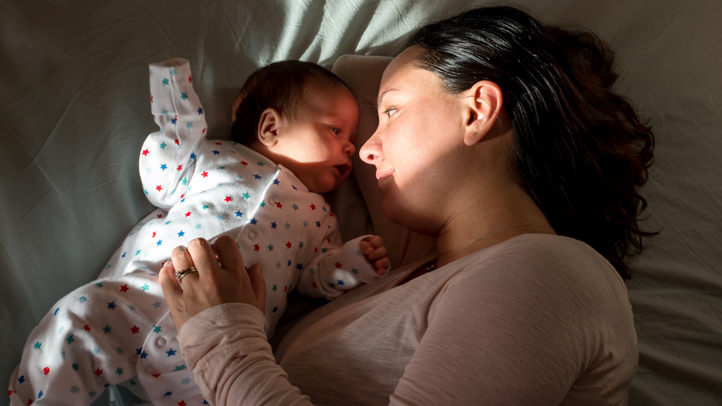 mom snuggling with baby in star pajamas, baby names by astrological sign
