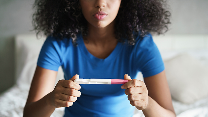 can you get pregnant if you're not ovulating, anovulation, woman looking at a home pregnancy test