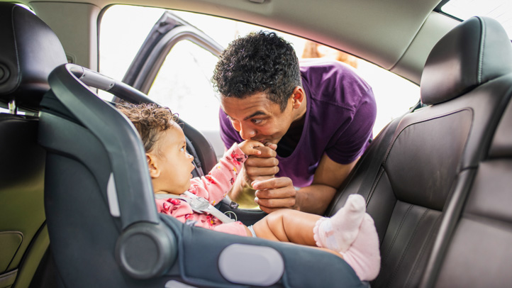 Dad putting baby in car seat
