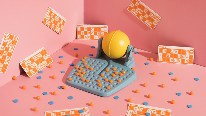 coed baby shower, blue bingo machine on pink background with yellow bingo cards and bingo markers