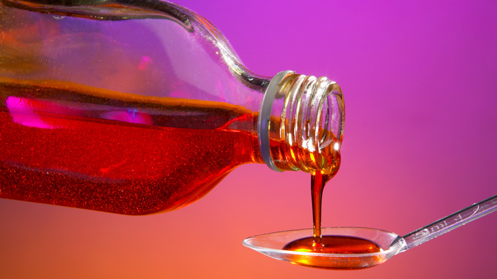 is dayquil safe during pregnancy and while breastfeeding, bottle of liquid medicine being poured into a teaspoon