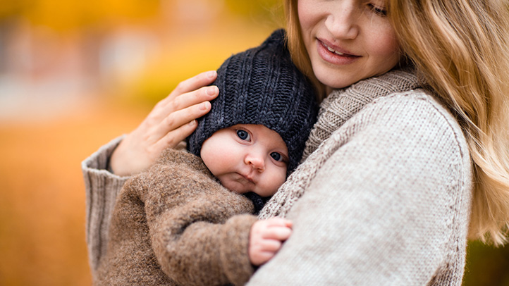 mom holding baby with fall colors in background, fall baby names
