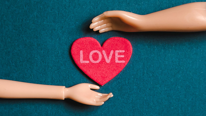 Two hands circling around a heart that says "love"