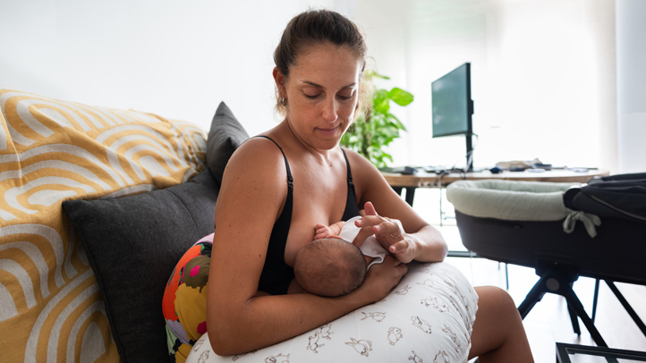 mom using nursing pillow to breastfeed baby