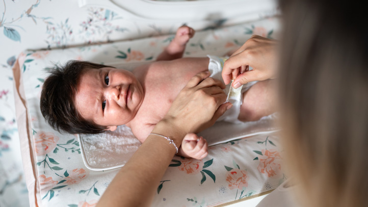 Diaper Blowout Cleanup Tips: A baby looking uncomfortable while getting their diaper changed. 