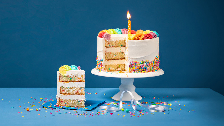 how to plan first birthday party, birthday cake with one lit candle and one slice cut out of it